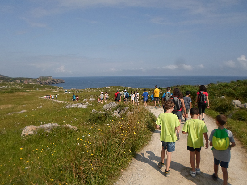 Grupo de niños y adultos haciendo senderismo en la costa.